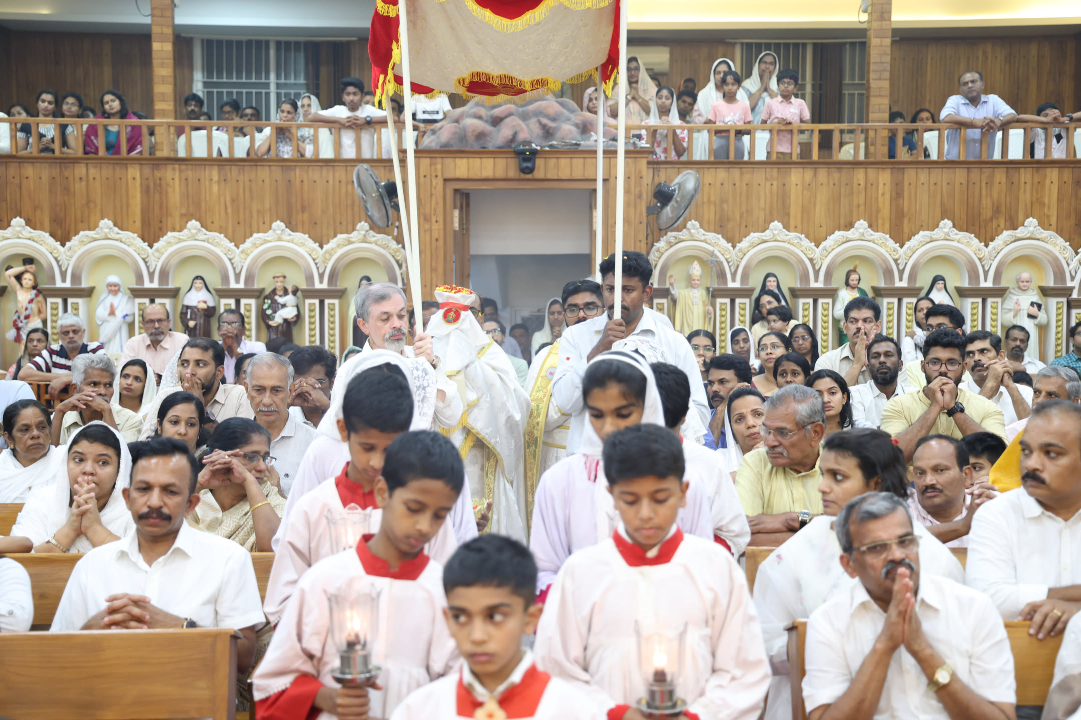 Holy Week procession led by altar servers beneath a ceremonial canopy